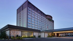 A multi-story hotel with a modern design, featuring a large entrance with a covered area and a parking lot. - Skybridge Seattle Airport Hotel (SeaTac)