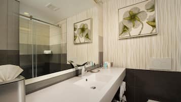 A modern bathroom with a large mirror, a sink, and a shower.