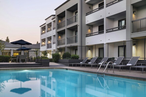 Relax by the pool surrounded by lounge chairs and umbrellas.