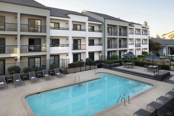 Un hôtel à plusieurs étages doté d’une piscine, d’un espace extérieur aménagé et d’un jardin bien entretenu.