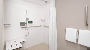 A shower area with a handheld showerhead, a glass-enclosed shower, and a white shower curtain.