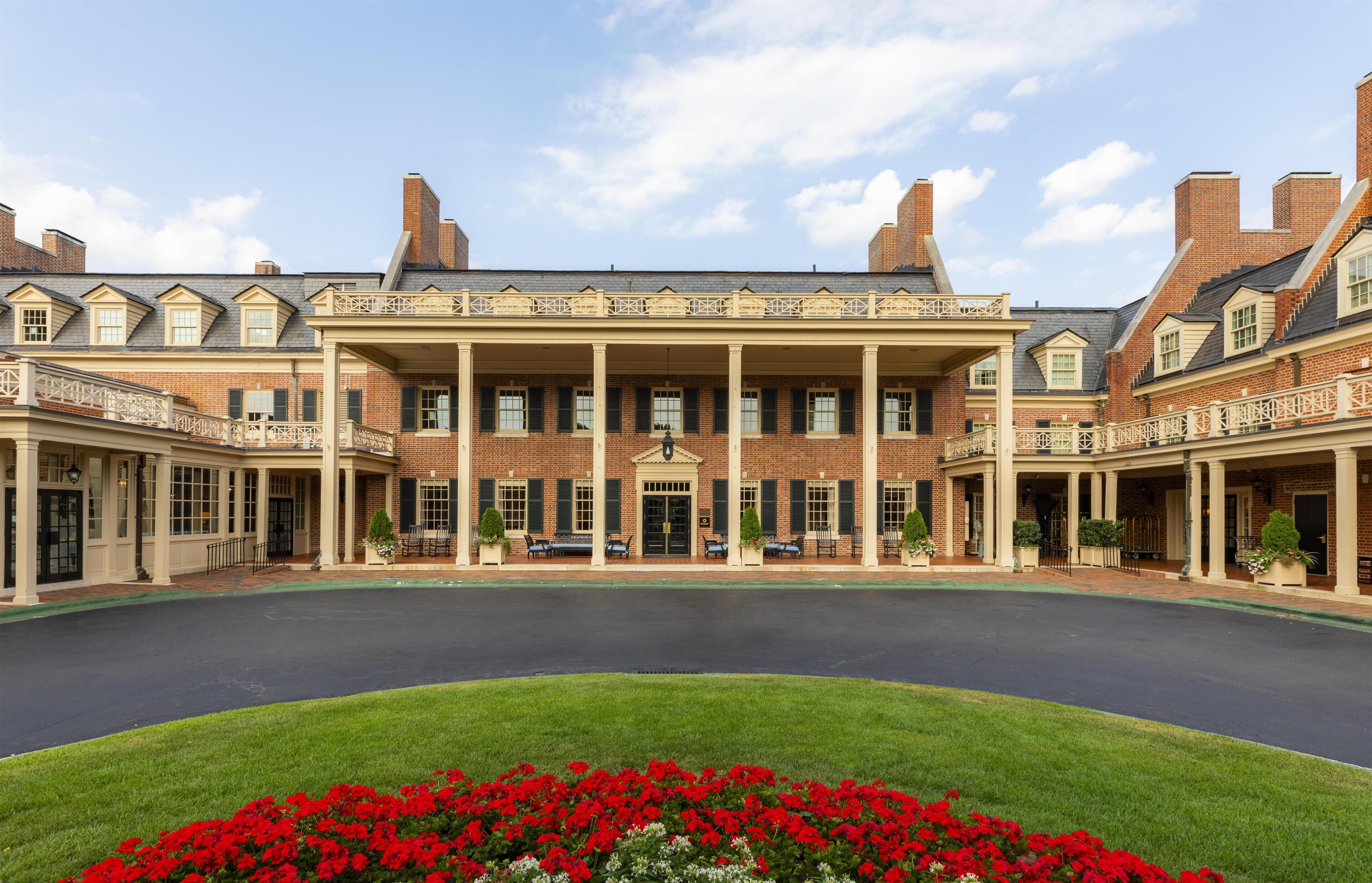A large brick building with a central entrance, multiple balconies, and a courtyard.