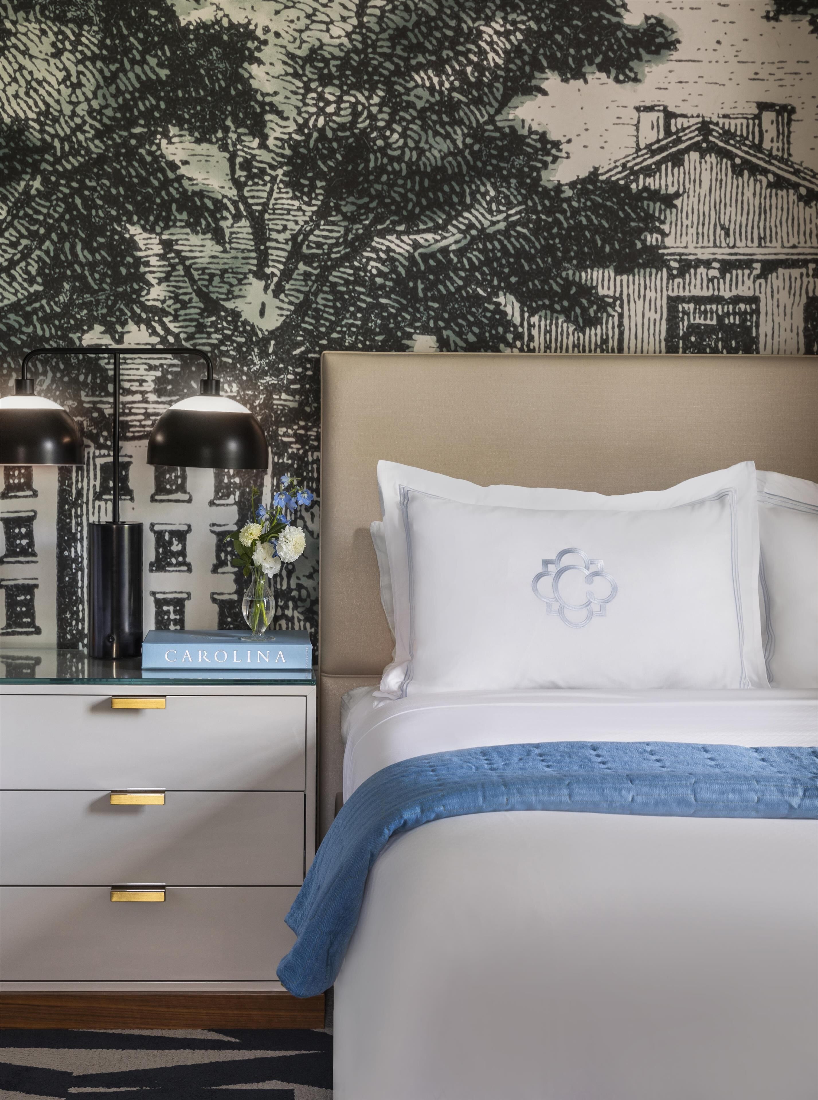 Une chambre à coucher bien rangée, avec un lit, des tables de chevet et une lampe fixée au mur.