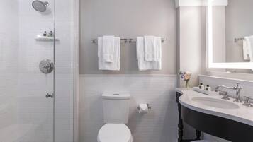 Ein Badezimmer mit Duschkabine, Toilette, Waschbecken mit Spiegel und zwei Handtuchhaltern.