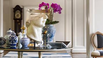 A room with a chandelier, a bust sculpture, and decorative vases on a table.