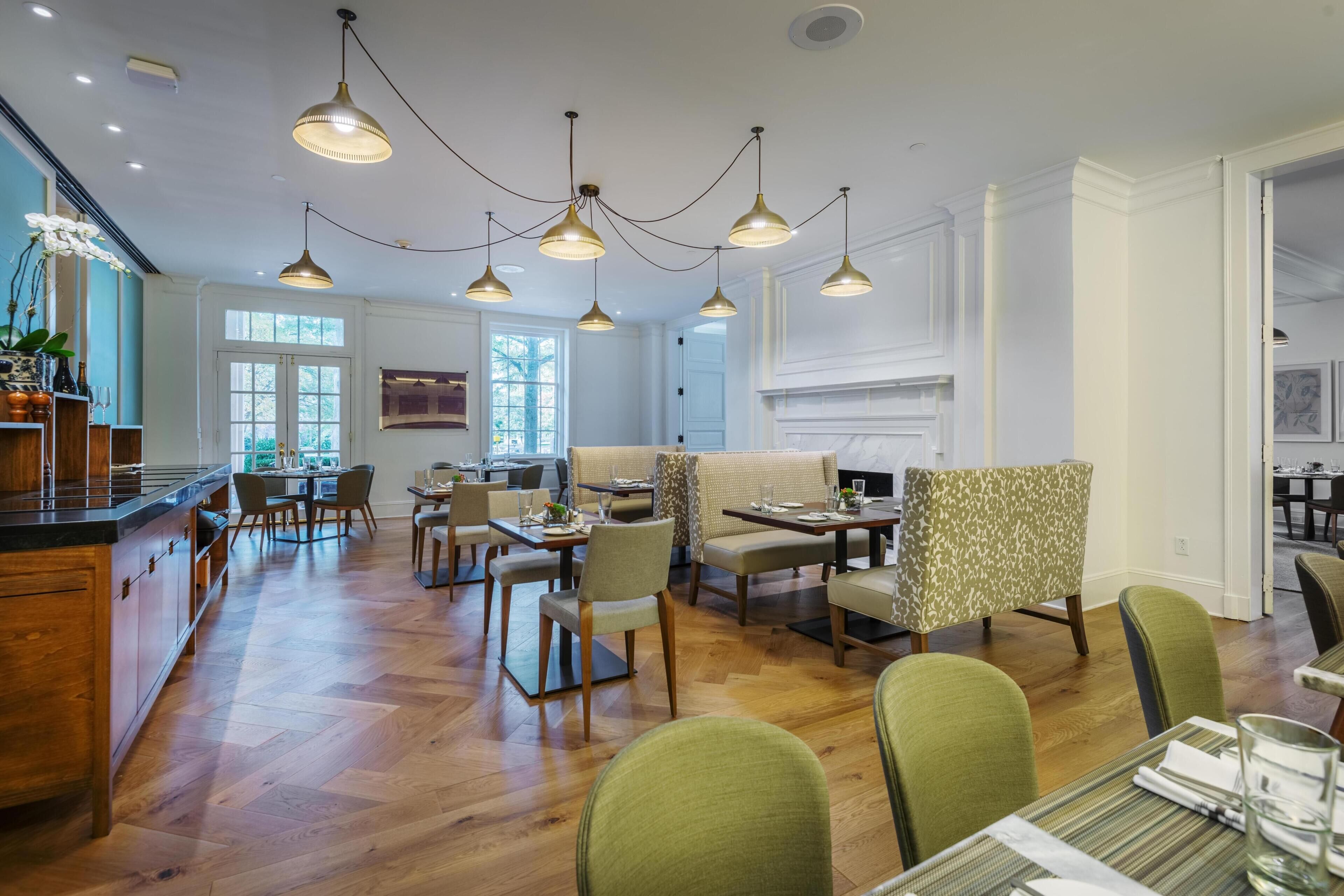 A spacious dining area with multiple tables and chairs, a kitchen area with a bar, and a fireplace.
