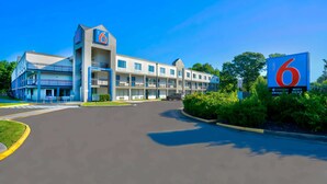 Un motel avec un grand panneau indiquant le chiffre « 6 », de nombreux balcons et un ciel dégagé.