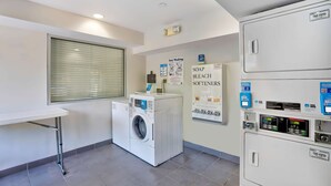 Une buanderie équipée d’un lave-linge à chargement frontal, d’un sèche-linge et d’un distributeur de lessive fixé au mur.