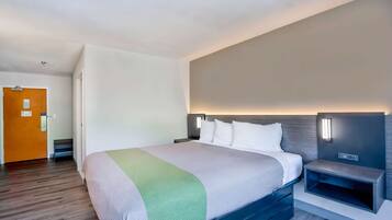 A hotel room with a large bed, bedside tables, a nightstand, and a wall-mounted TV.