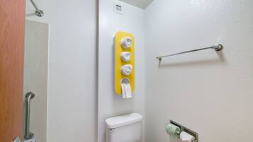 Un baño con inodoro, perchero para toallas y dispensador de papel higiénico.