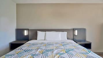 A modern hotel room with a large bed, two bedside tables, and wall-mounted lamps.