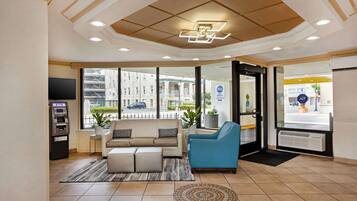 A hotel lobby with a sofa, armchair, and an ATM machine.