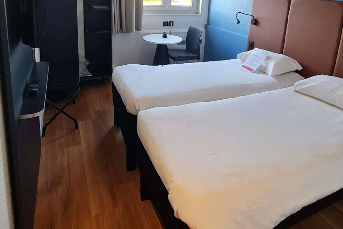 A room with two beds, a small table, and a chair.