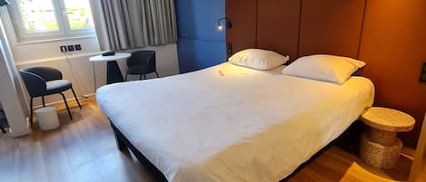 Une chambre d’hôtel moderne, dotée d’un grand lit, d’un bureau et d’une chaise.