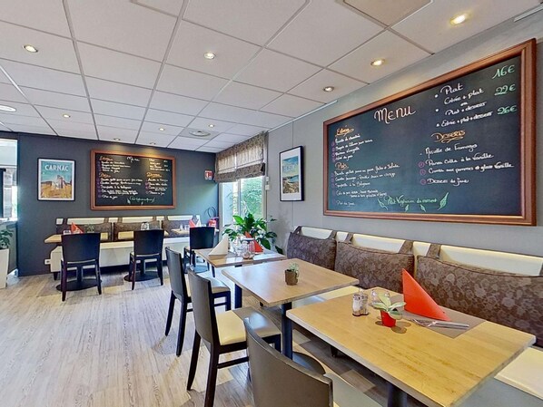 A restaurant with a chalkboard menu, seating area, and a view of the outdoors. - Hotel ibis Vannes (Vannes)