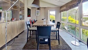 A modern dining area with a long table, black chairs, a large floor lamp, and a view of greenery through large windows. - Hotel ibis Vannes (Vannes)