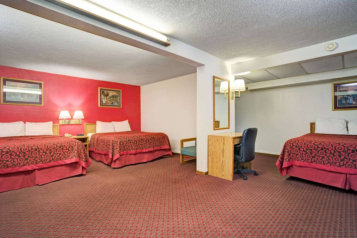 A hotel room with two beds, a desk, and a chair.