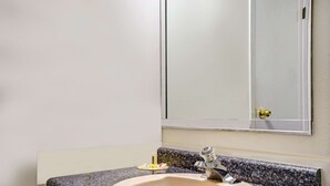 A bathroom with a granite countertop sink, a mirror, and a towel rack. - Travelodge by Wyndham Red Wing (Red Wing)