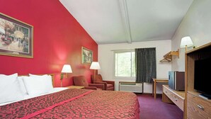 A hotel room with a large bed, a desk with a television, a chair, and a window with curtains. - Travelodge by Wyndham Red Wing (Red Wing)