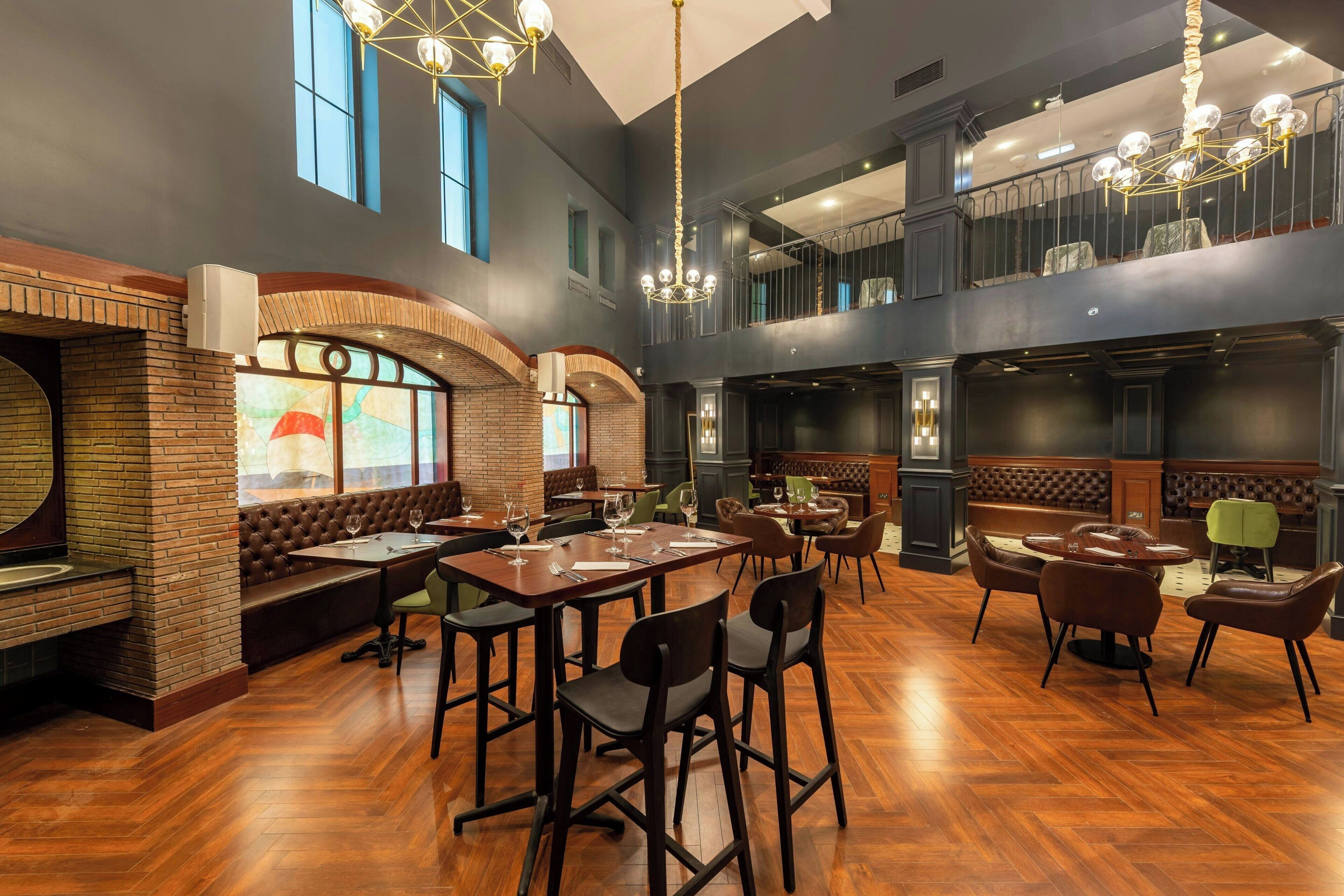 A spacious restaurant with high ceilings, exposed brick walls, and a variety of seating options including booths and tables.