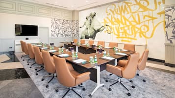 A conference room with a long table, multiple chairs, and a large mural on the wall.