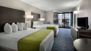 Quarto de hotel com duas camas, televisão, escrivaninha e vista para a varanda externa.