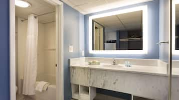Een badkamer met een wastafel van wit marmer, een grote spiegel en een douchegordijn.