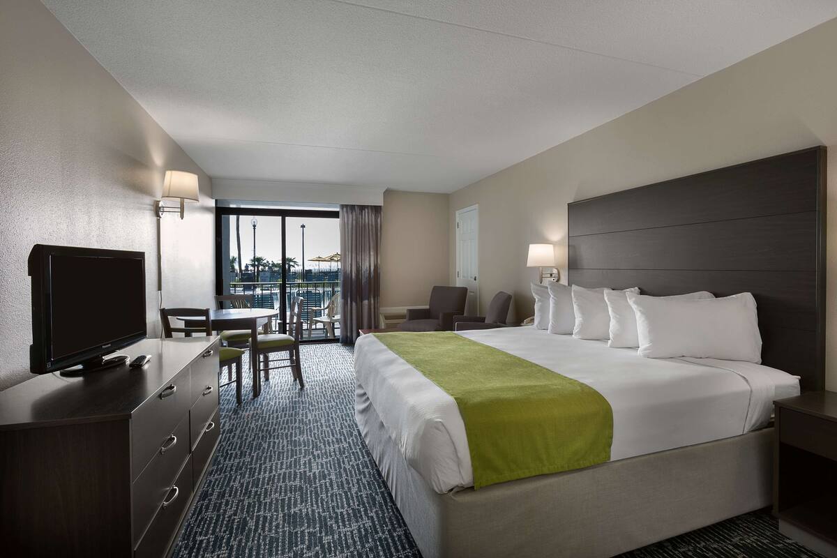 Une chambre d’hôtel avec un grand lit, une télévision, un bureau et une chaise.