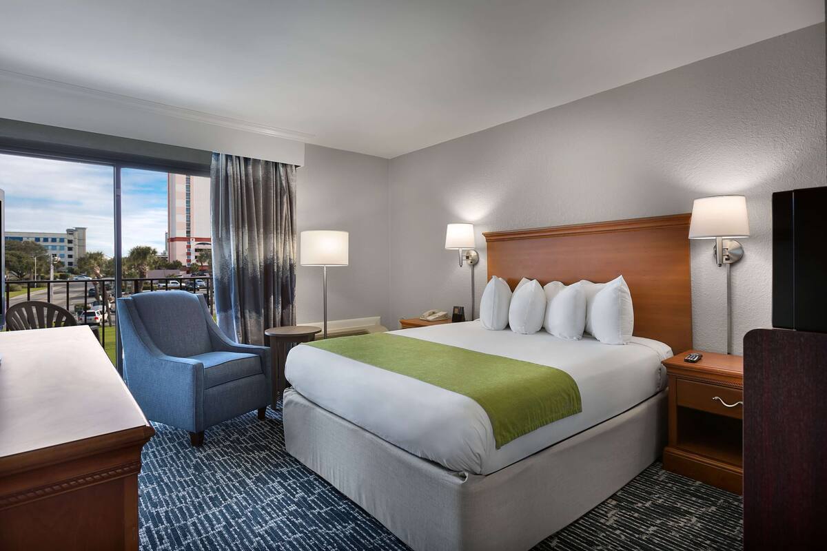 Une chambre d’hôtel avec un grand lit, un bureau, une chaise et une télévision.