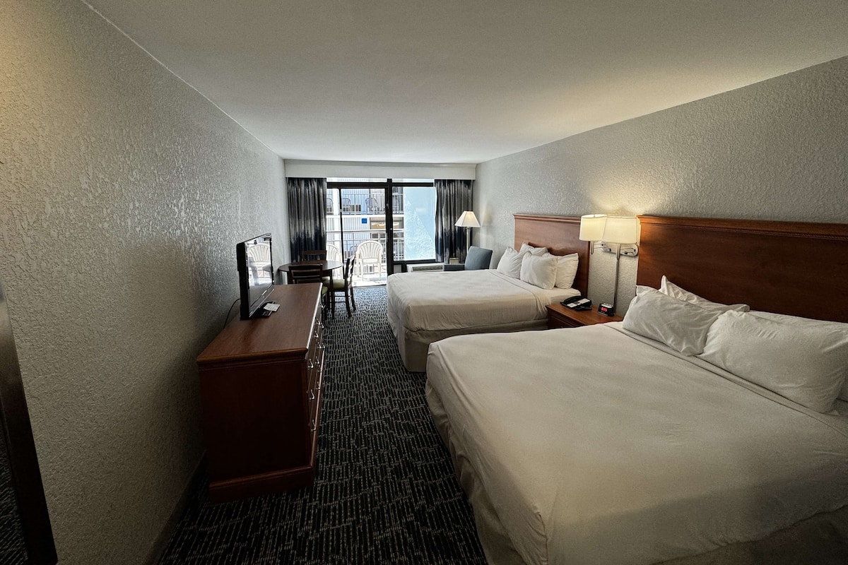 Une chambre d’hôtel avec deux lits, un bureau et une chaise.