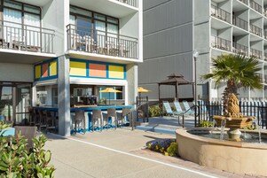 Un hotel con terraza al aire libre, bar y una fuente.