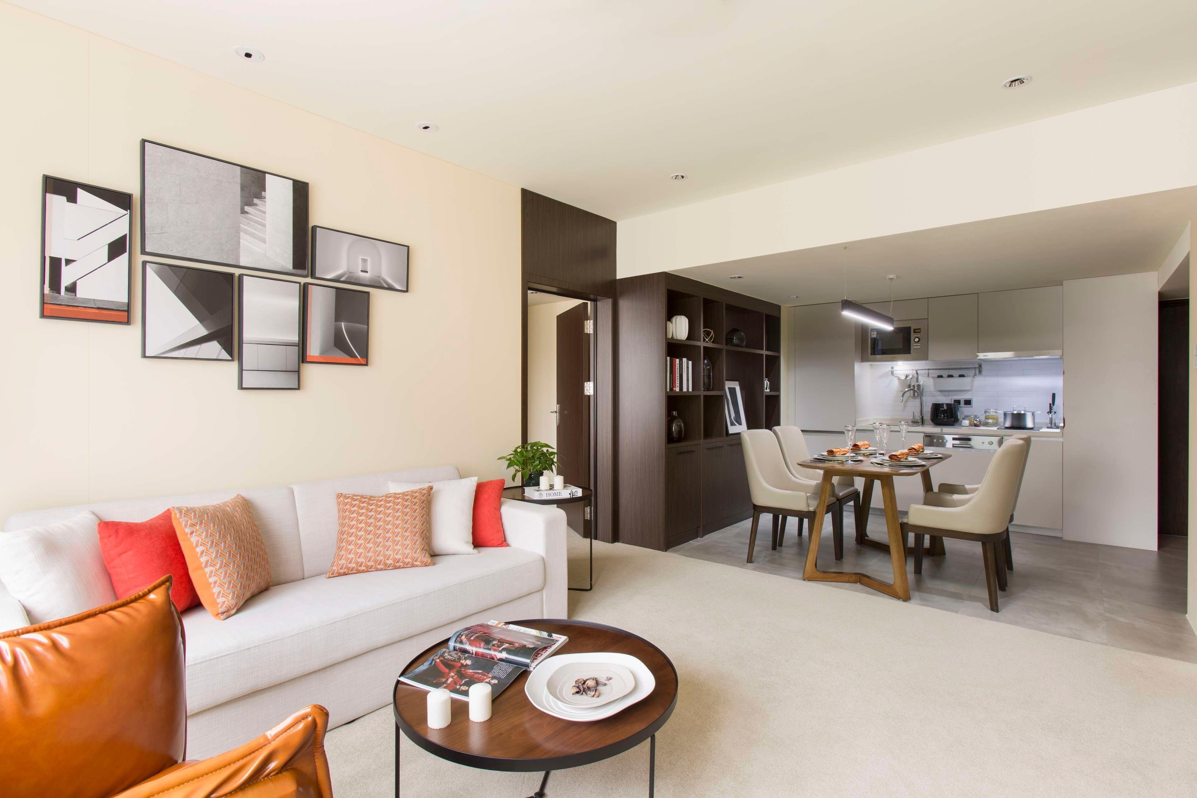 A modern living room with a sofa, coffee table, and dining area with chairs.