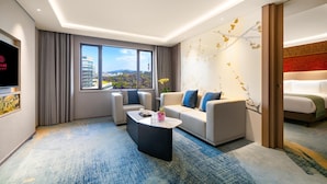 Una habitación de hotel moderna con un ventanal grande, un sofá, una mesa de centro y una cama.
