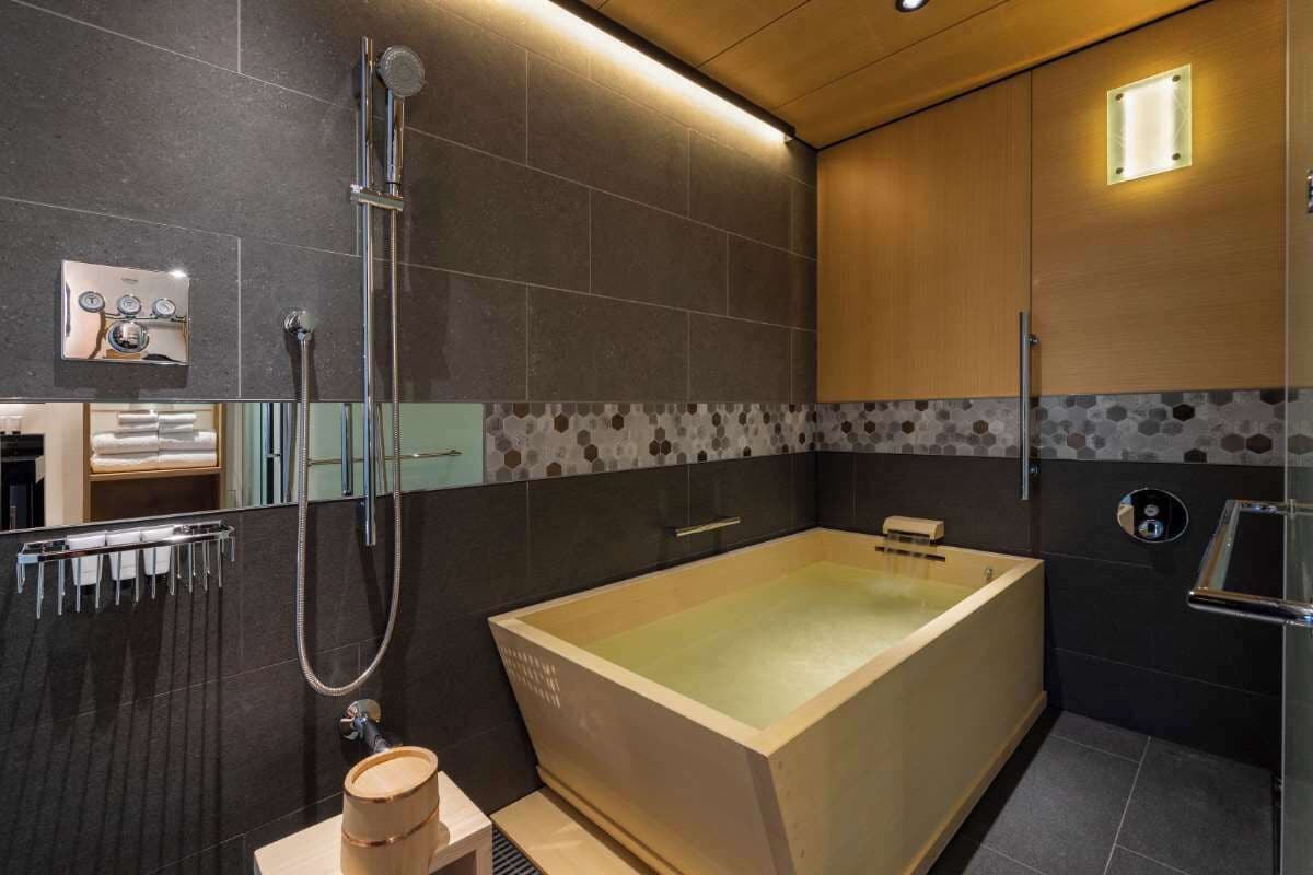A modern bathroom with a large bathtub, a shower, and a vanity with a mirror.