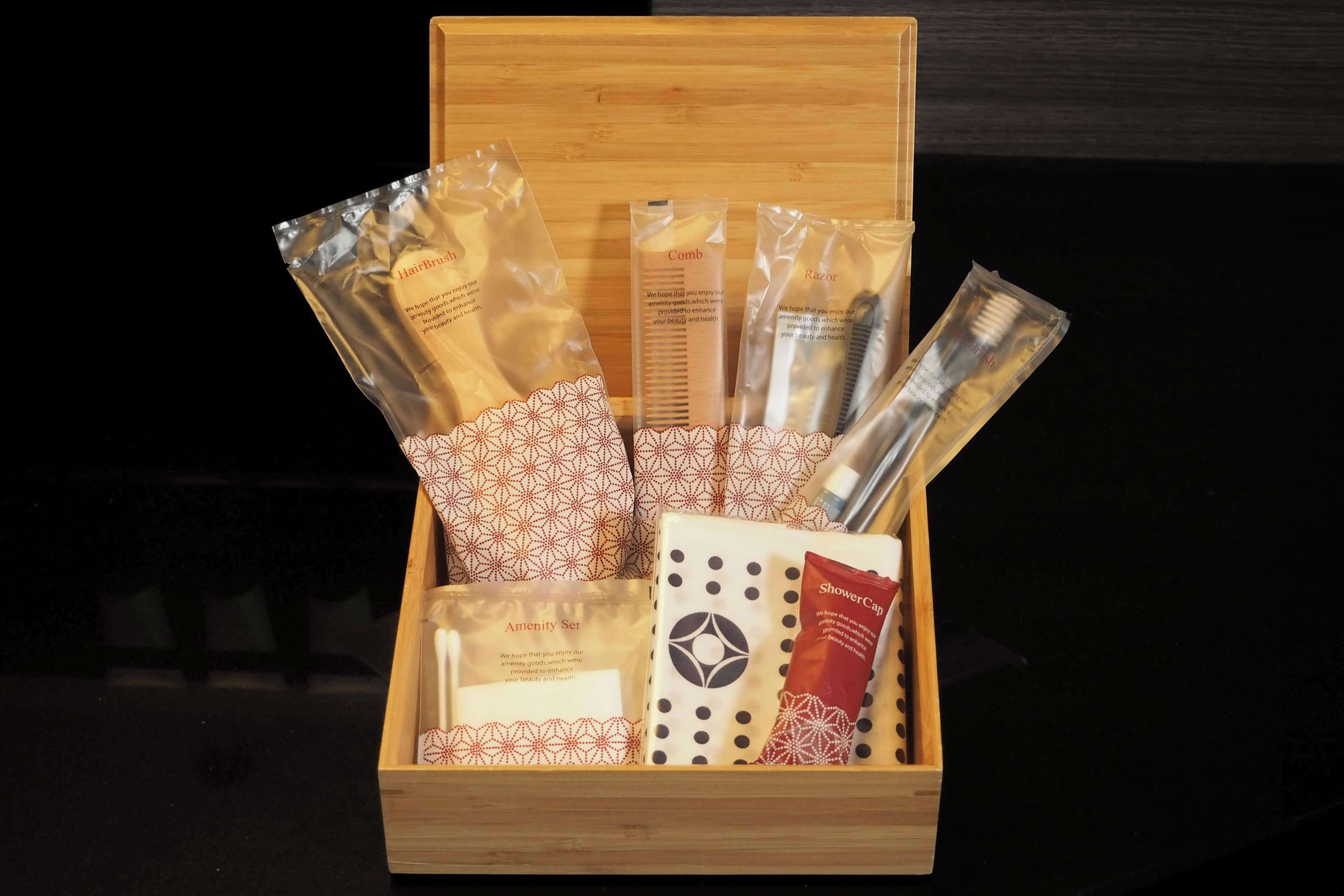 A wooden box containing various personal care items such as hairbrushes, combs, razors, and a shower cap.