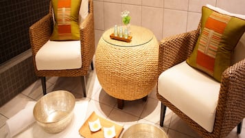 A seating area with wicker chairs and a woven table, accompanied by two bowls and a tray with a bottle and glass.