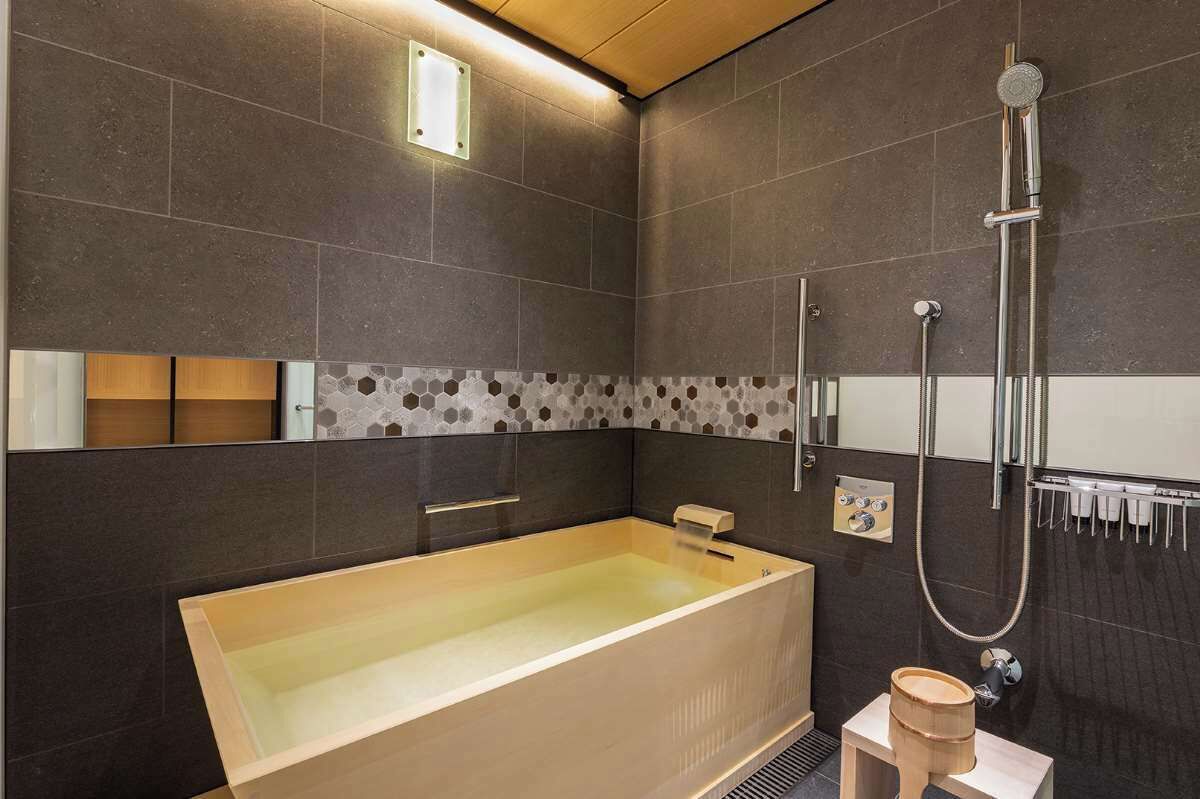 Ein modernes Badezimmer mit einer großen Badewanne, einer Duschkabine und einem kleinen hölzernen Hocker.