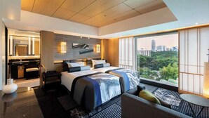 A modern hotel room with a city view, a large bed, a desk, and a bathroom.