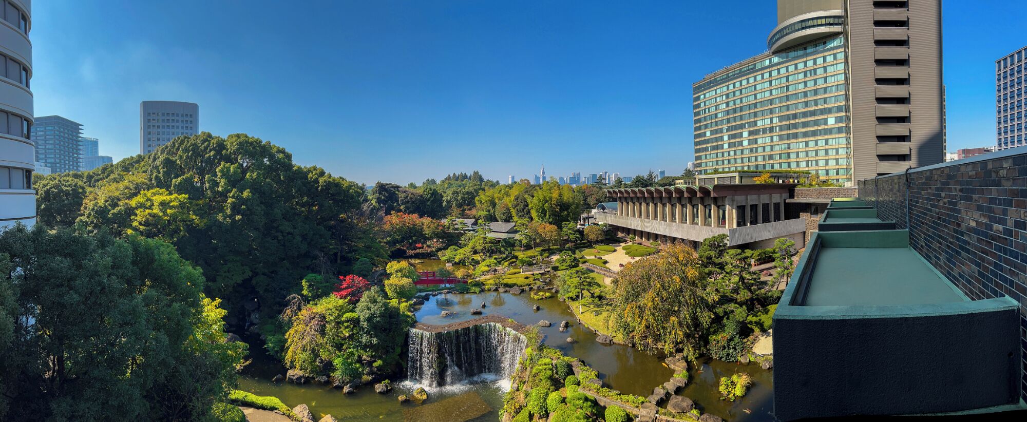 Un edificio moderno con fachada curva y jardín en la azotea.