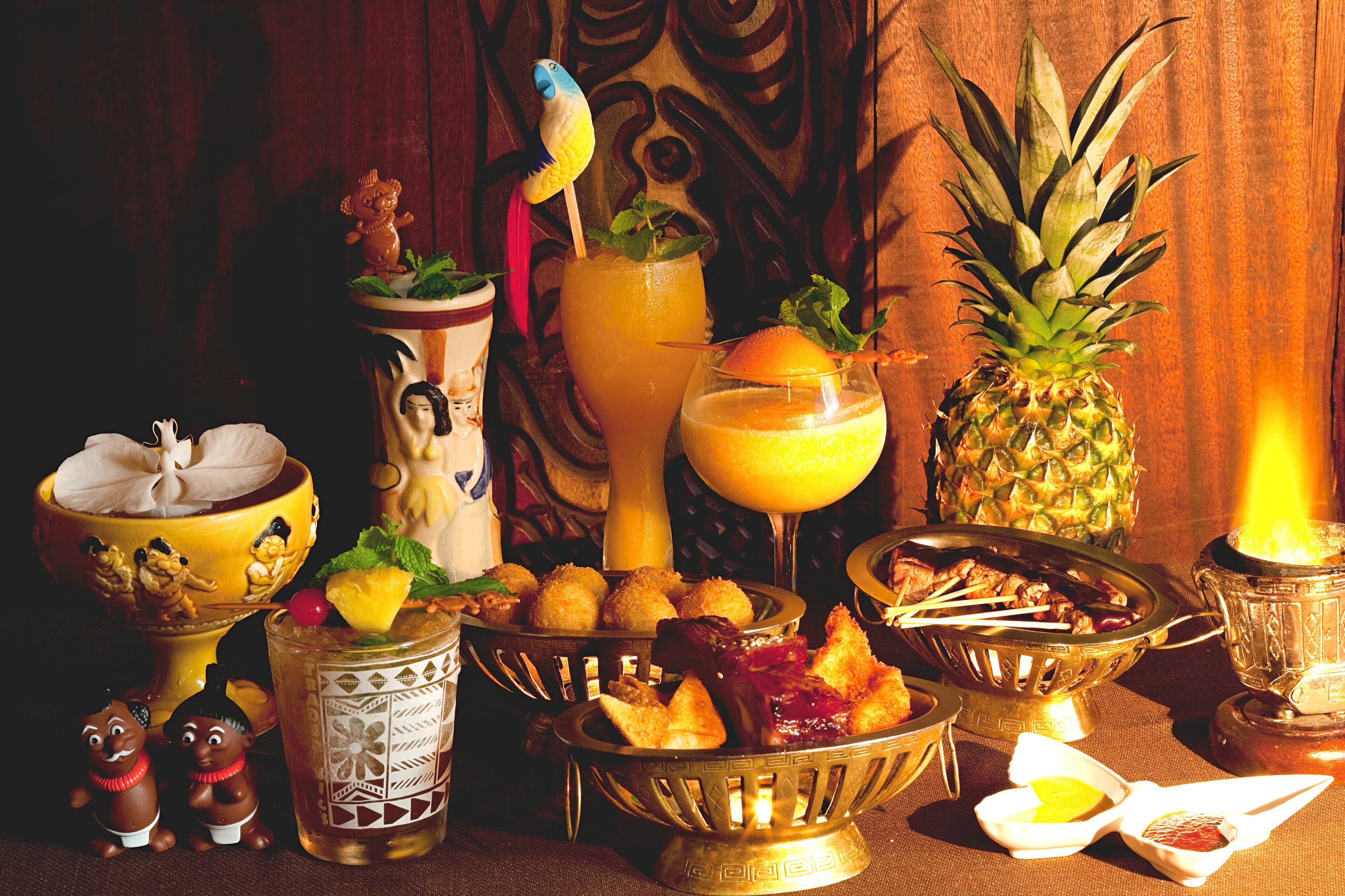 Una mesa decorada con motivos tropicales, bebidas, frutas y adornos.