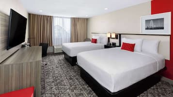 A hotel room with two beds, a TV, a desk, and a red chair.