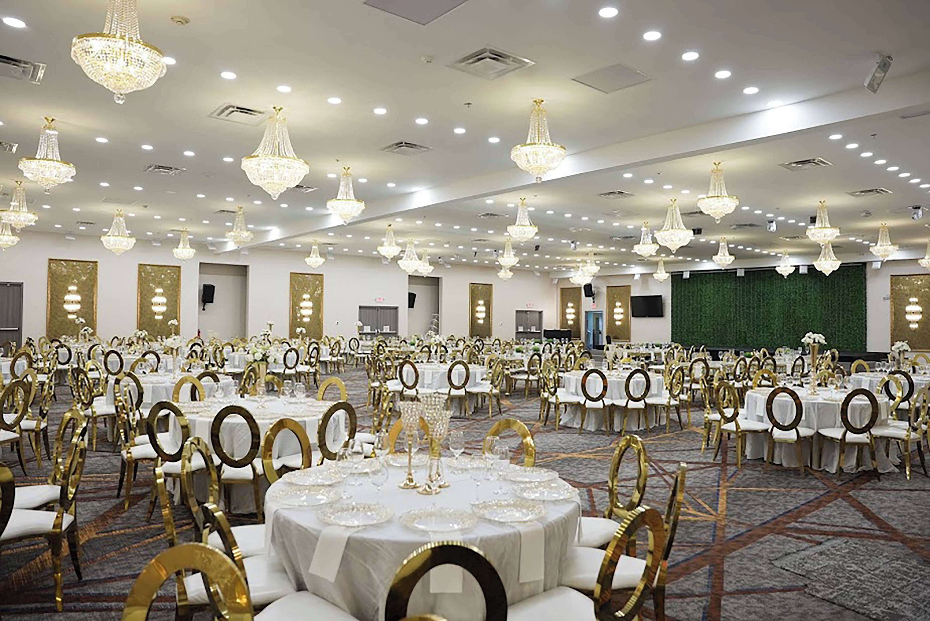 Un salón de banquetes con mesas redondas, sillas doradas y candelabros.