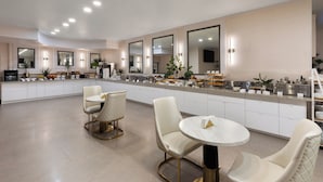 A modern kitchen with white cabinetry, a central island, and two white dining chairs.