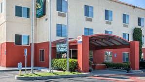 A hotel with a sign for "Quality Inn" and flags of the USA, UAE, and Qatar. - Quality Inn Merced Gateway to Yosemite (Merced)