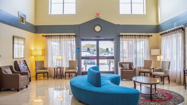 A lobby with a blue sofa, multiple armchairs, a round table, and a clock on the wall. - Quality Inn Merced Gateway to Yosemite (Merced)