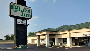 A Plaza Inn hotel with a sign indicating weekly, monthly, and daily kitchenettes, HBO Family, and HBO. The building has a 'Lobby' sign and a 'Low Clearance 9 FT' sign. - Topeka Plaza Inn (Topeka)