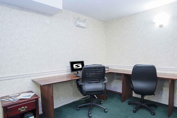 A corner office with two desks, a computer monitor, and a filing cabinet.