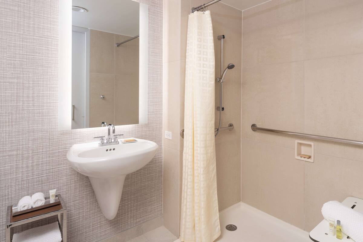 A modern bathroom with a white sink, mirror, and shower.