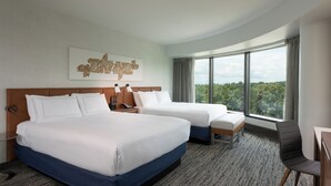 A hotel room with two beds, a large window with a view of trees, and a modern design. - Hilton Fairfax (Fairfax)