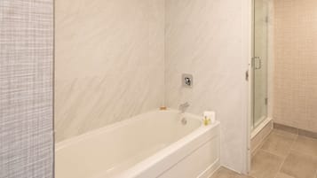 A modern bathroom with a large bathtub, a glass shower enclosure, and a tiled floor.